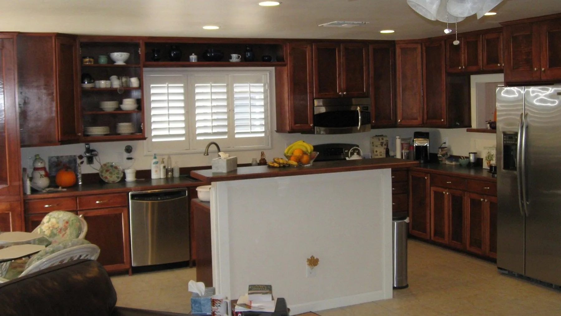 A kitchen built by Cabinetry and Custom Woodworks of Tucson, with stained raised panel cabinets, open display shelving, and a peninsula