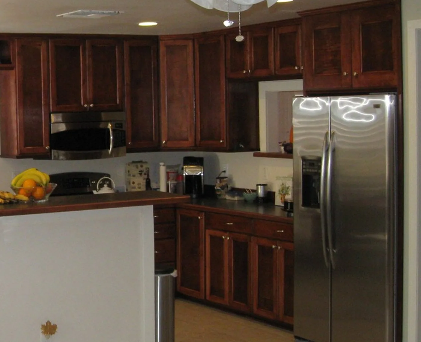 A run of stained raised panel kitchen cabinets with a wall microwave surround and a peninsula